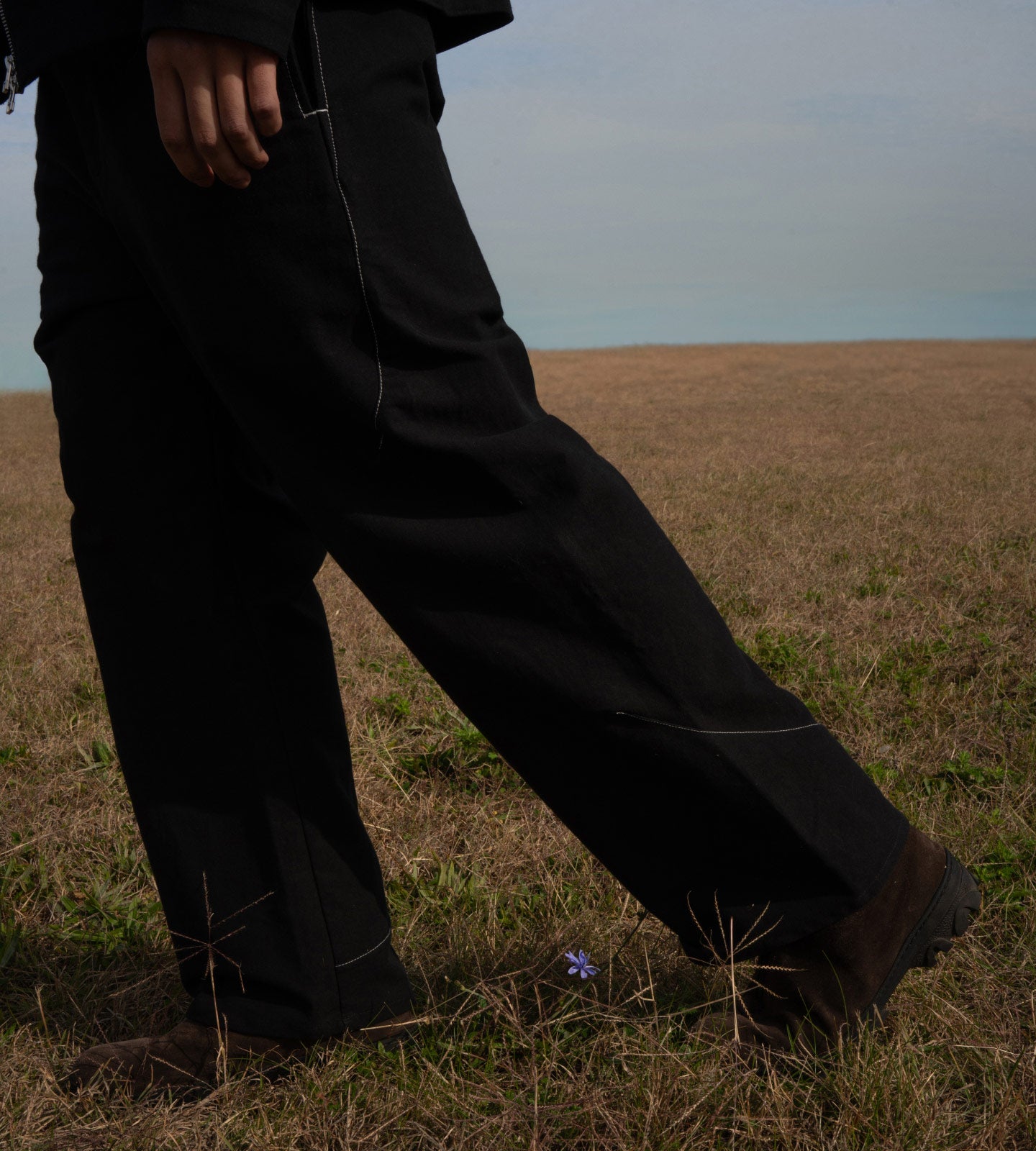 Person wearing black pants standing in a field with a blurred background